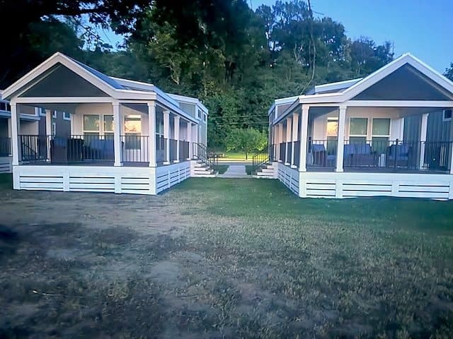 Two Riverbend homes at blue hour with porch lights on