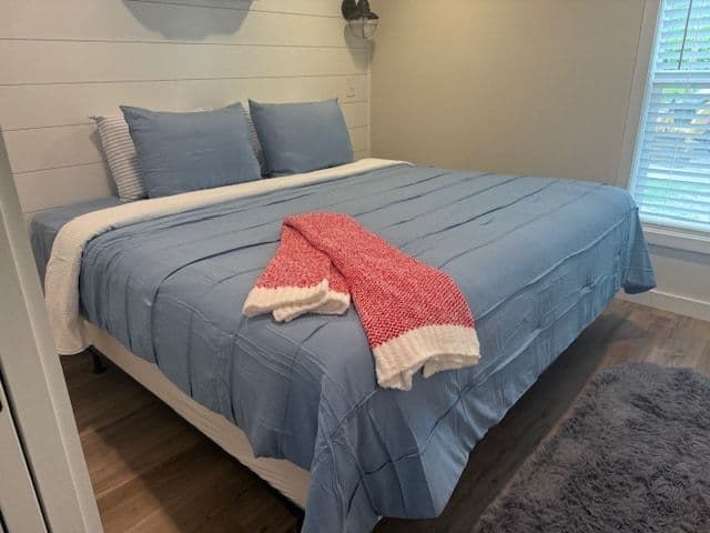 Bedroom, blue bed with red throw and pillows, window light