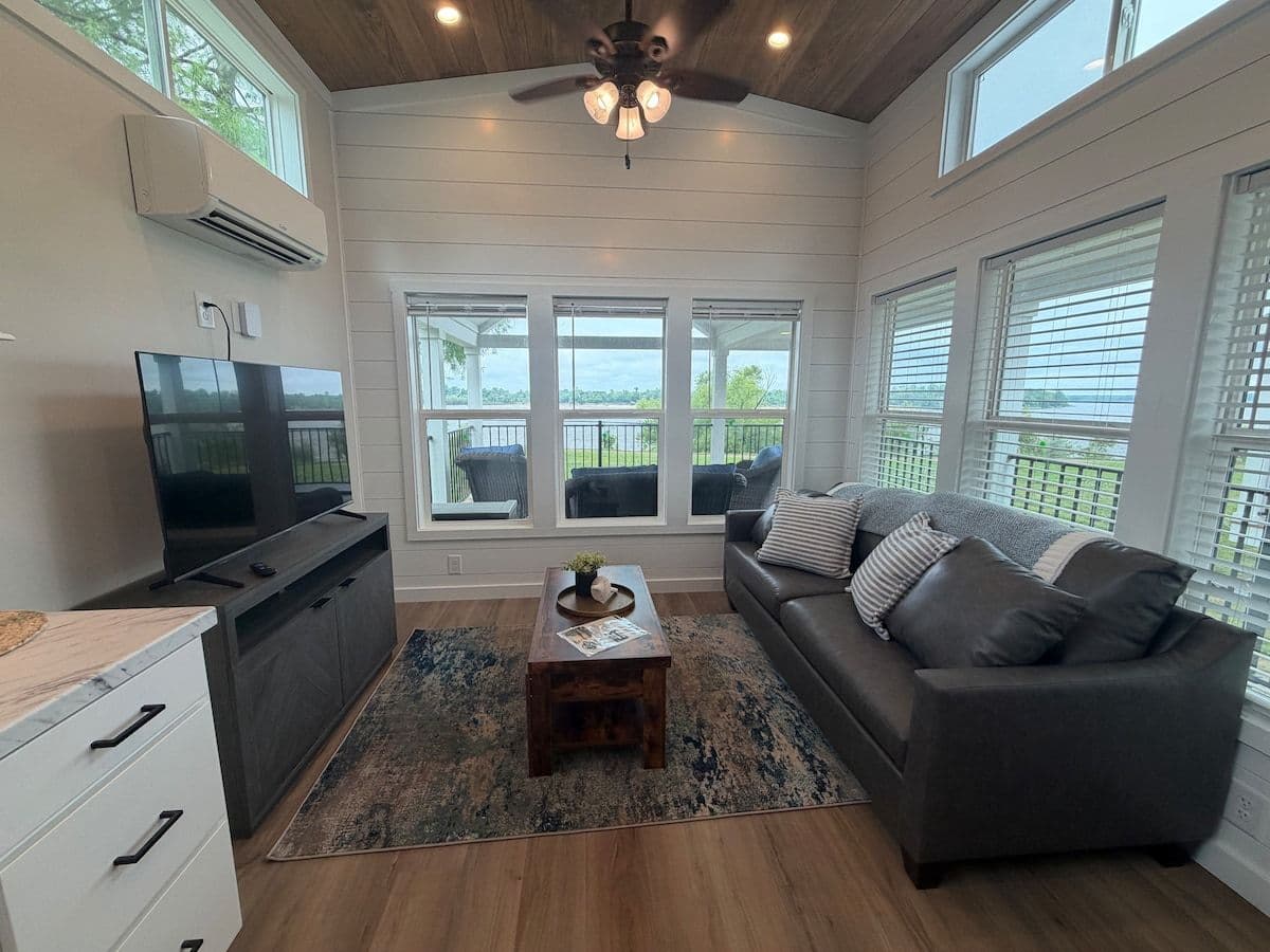Living room with TV console, gray sofa and tall windows