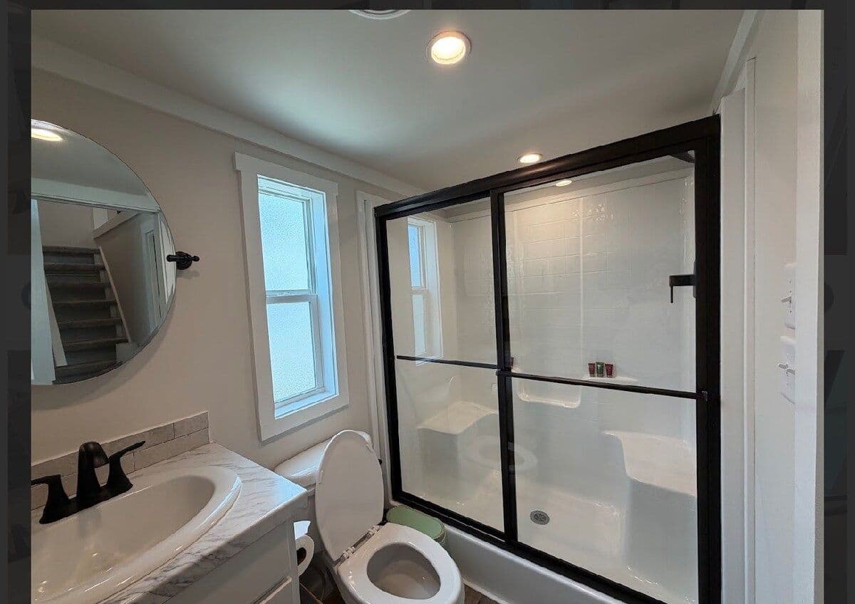 Bathroom with black-framed shower, black faucet and window