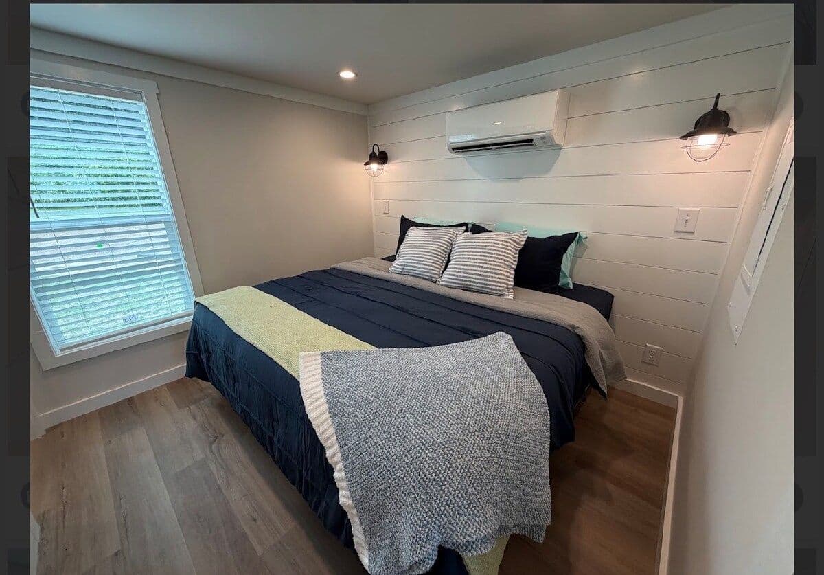 Bedroom with navy and yellow bedding, gray throw, wall AC