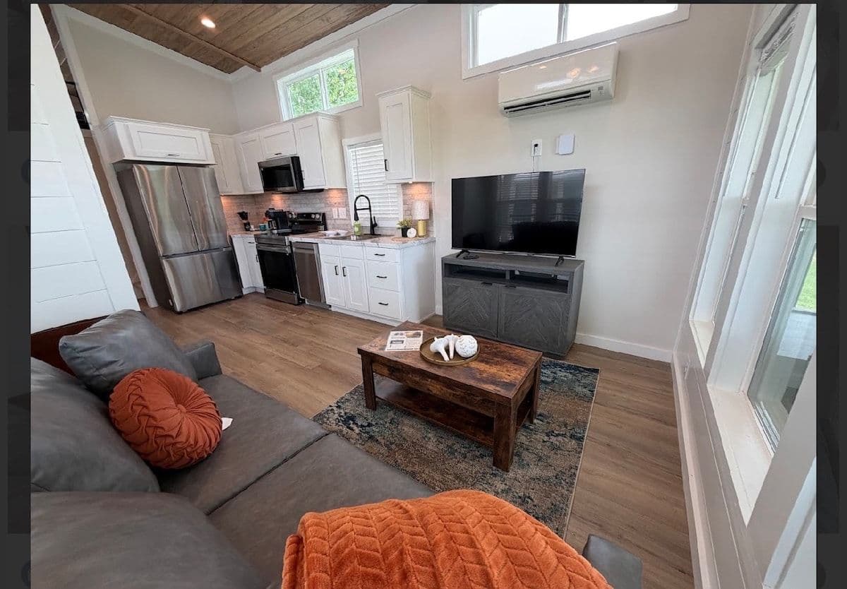 Living room with leather sofa, orange pillows, TV and wood coffee table