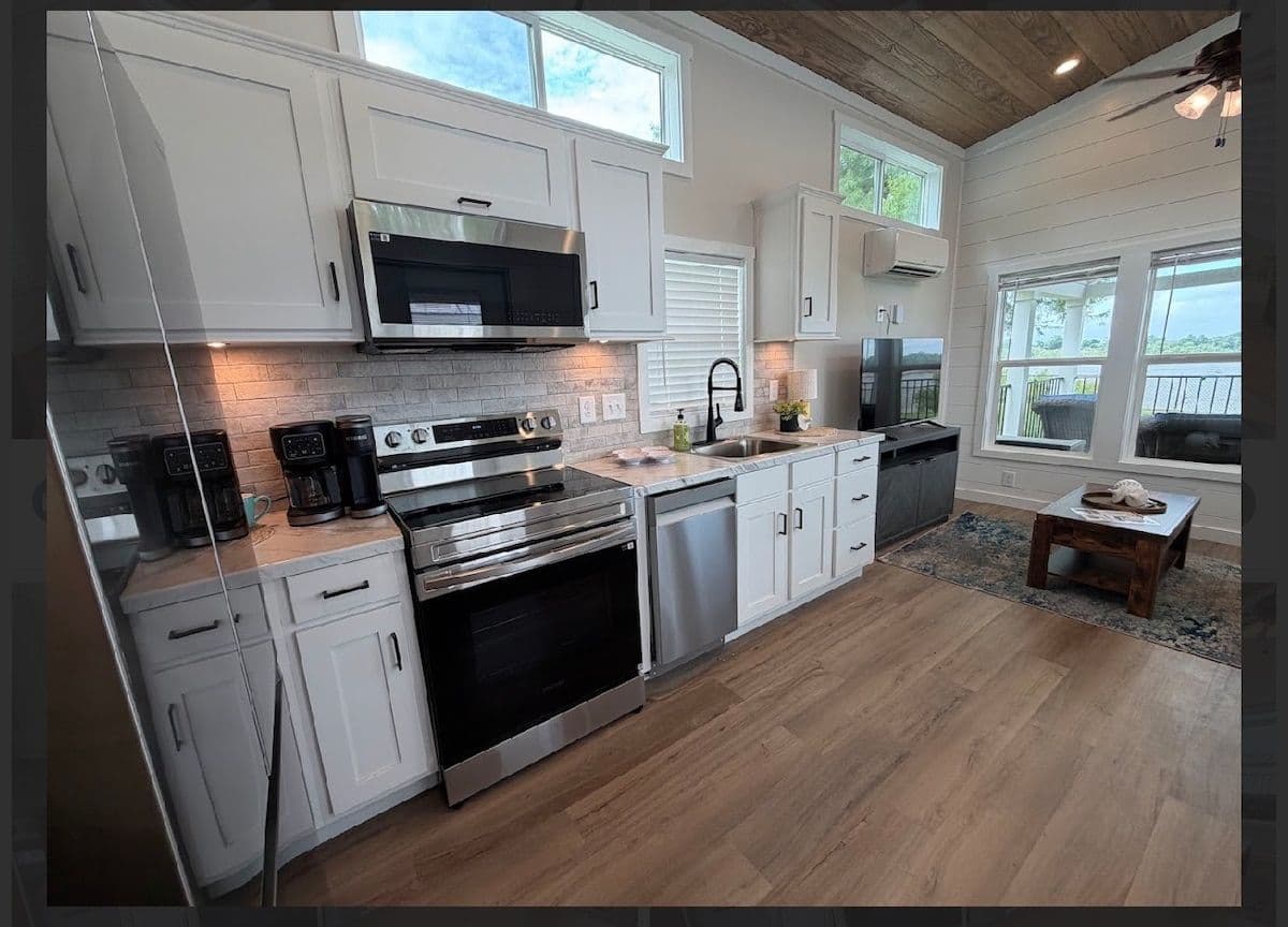 Kitchen with stainless range and microwave, white cabinets and wood floor