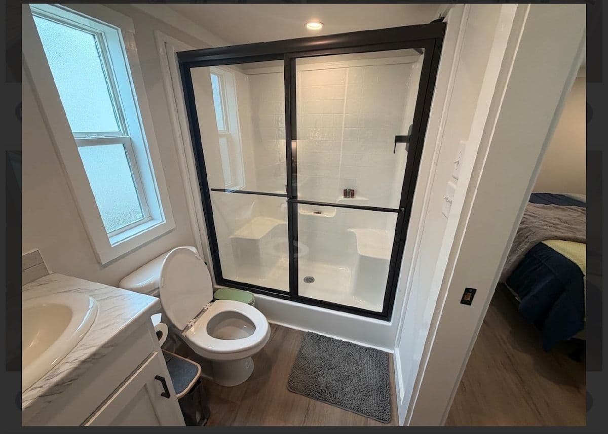 Bathroom with black-framed glass shower, window and vanity