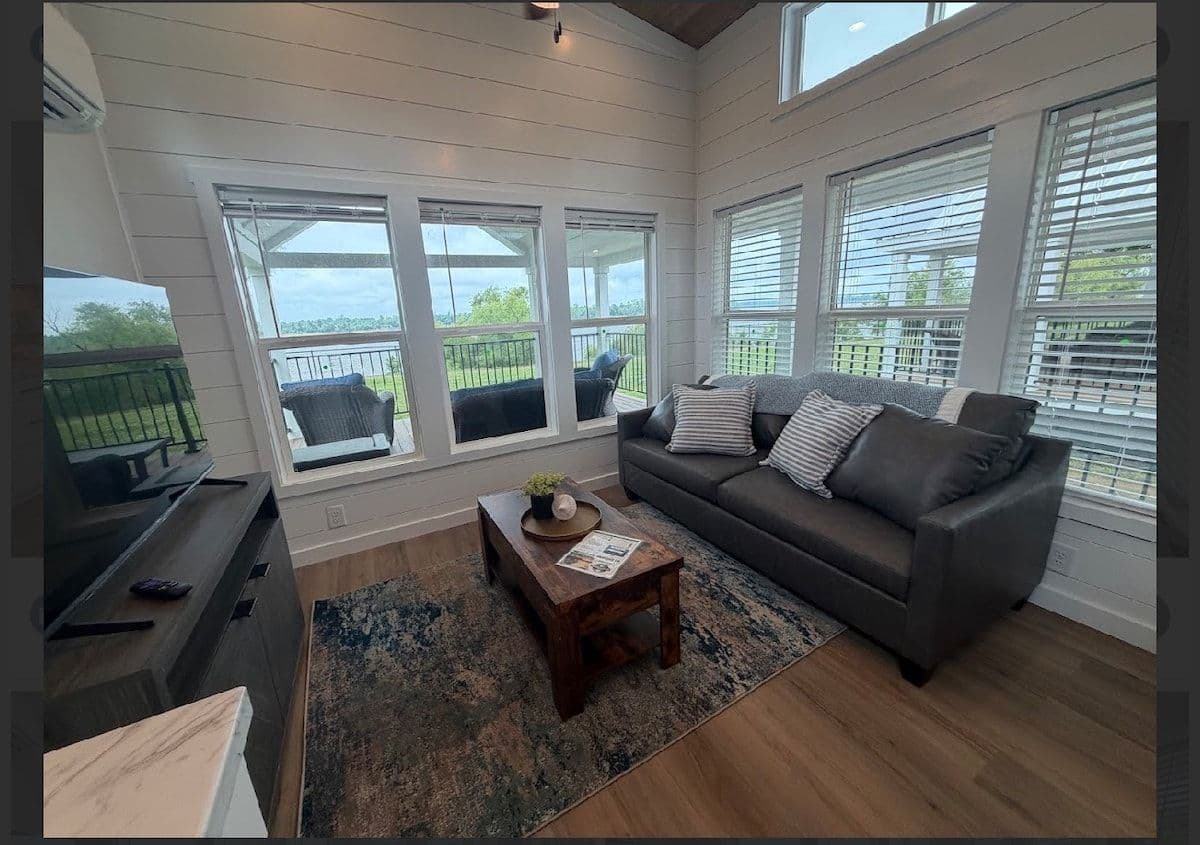 Living area with dark gray sofa, wood coffee table and wide windows