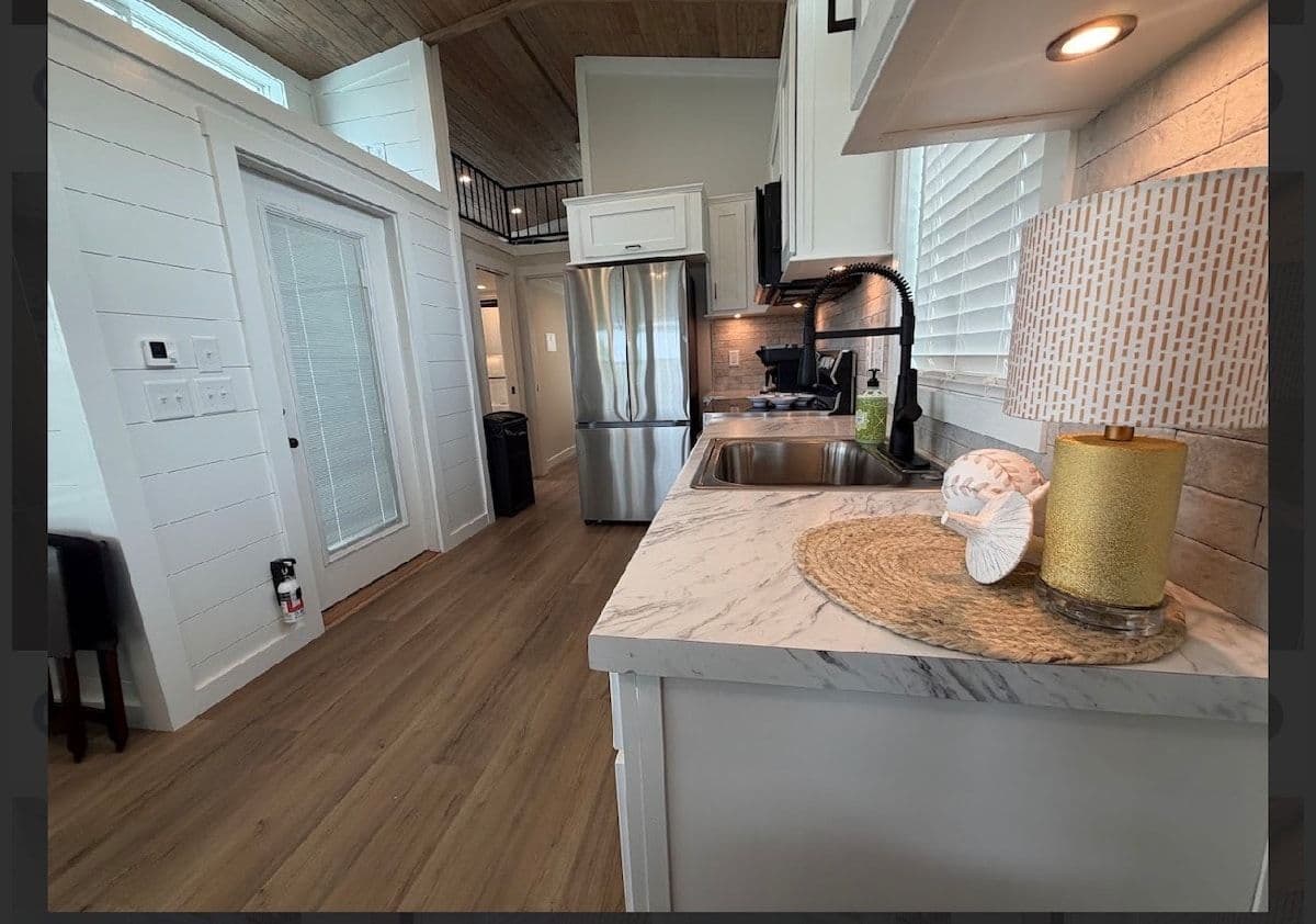 Kitchen counter and sink with marble top, fridge and door