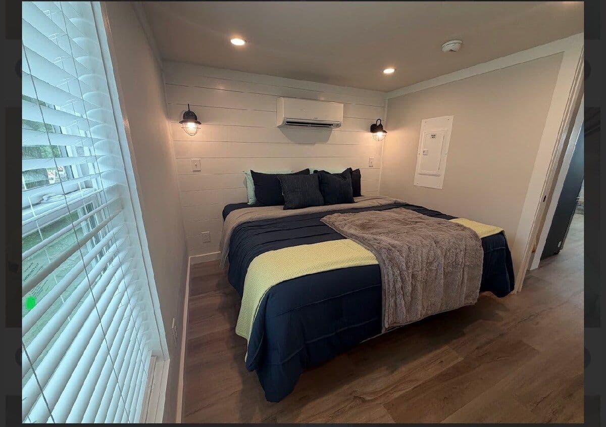 Bedroom from the foot of the bed with navy spread and sconce lights