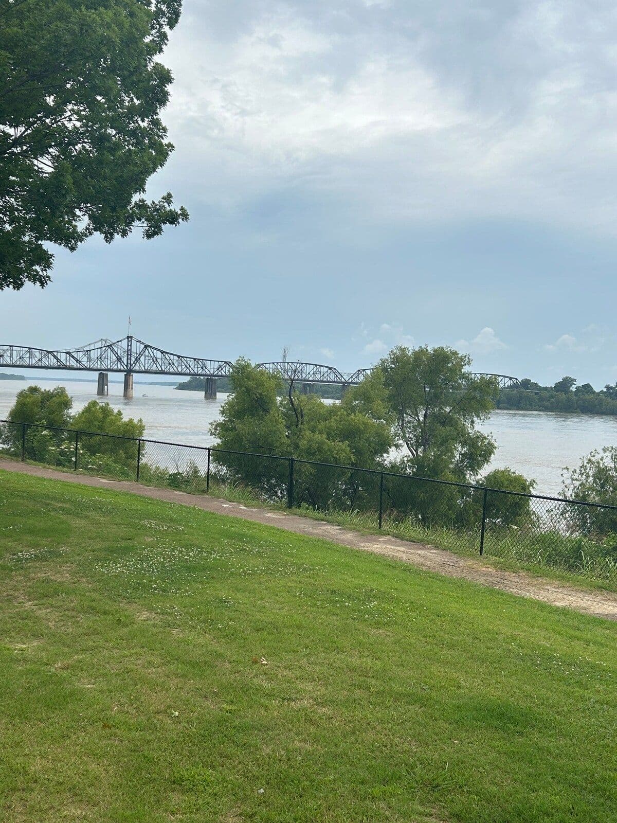 Lawn and river with the bridge in the distance