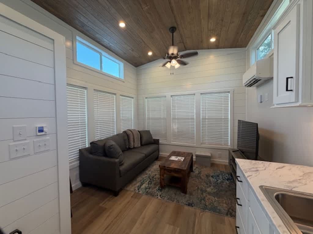 Living area with gray sofa, wood coffee table, ceiling fan