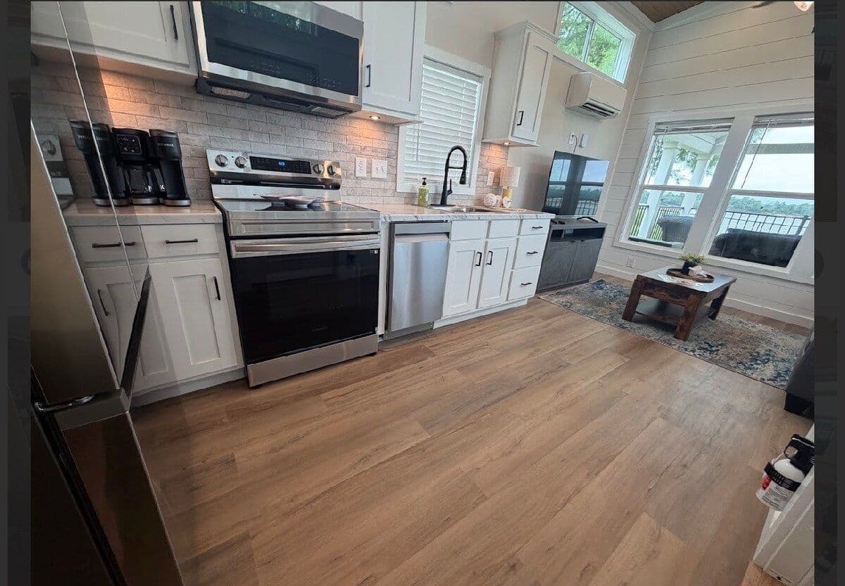 Kitchen with stainless range, microwave, white cabinets and windows