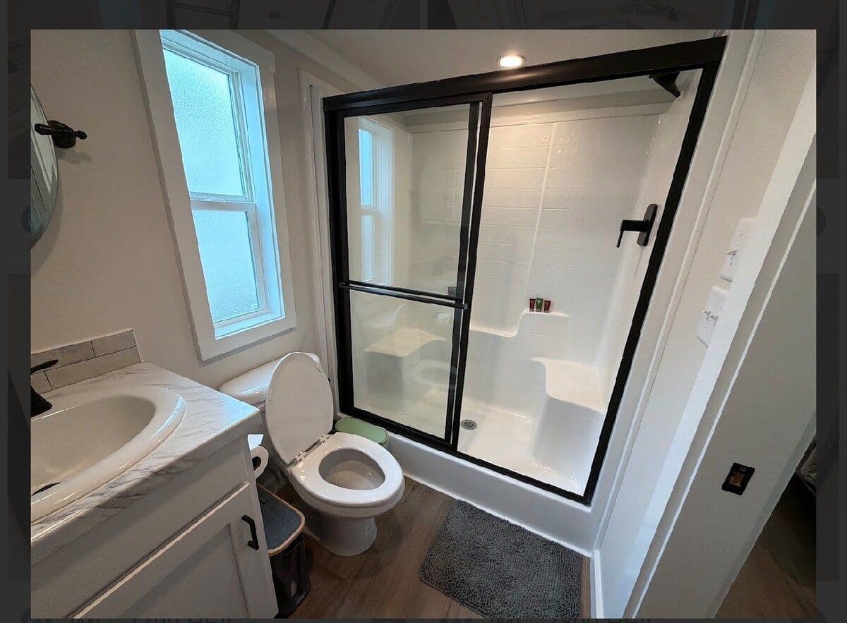 Bathroom with black-framed glass shower, window and toilet