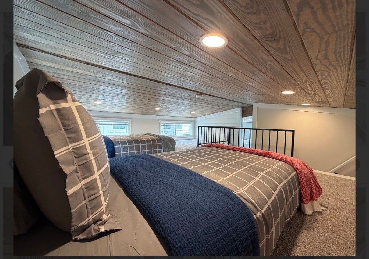 Loft bed with plaid pillows and navy blanket from the foot