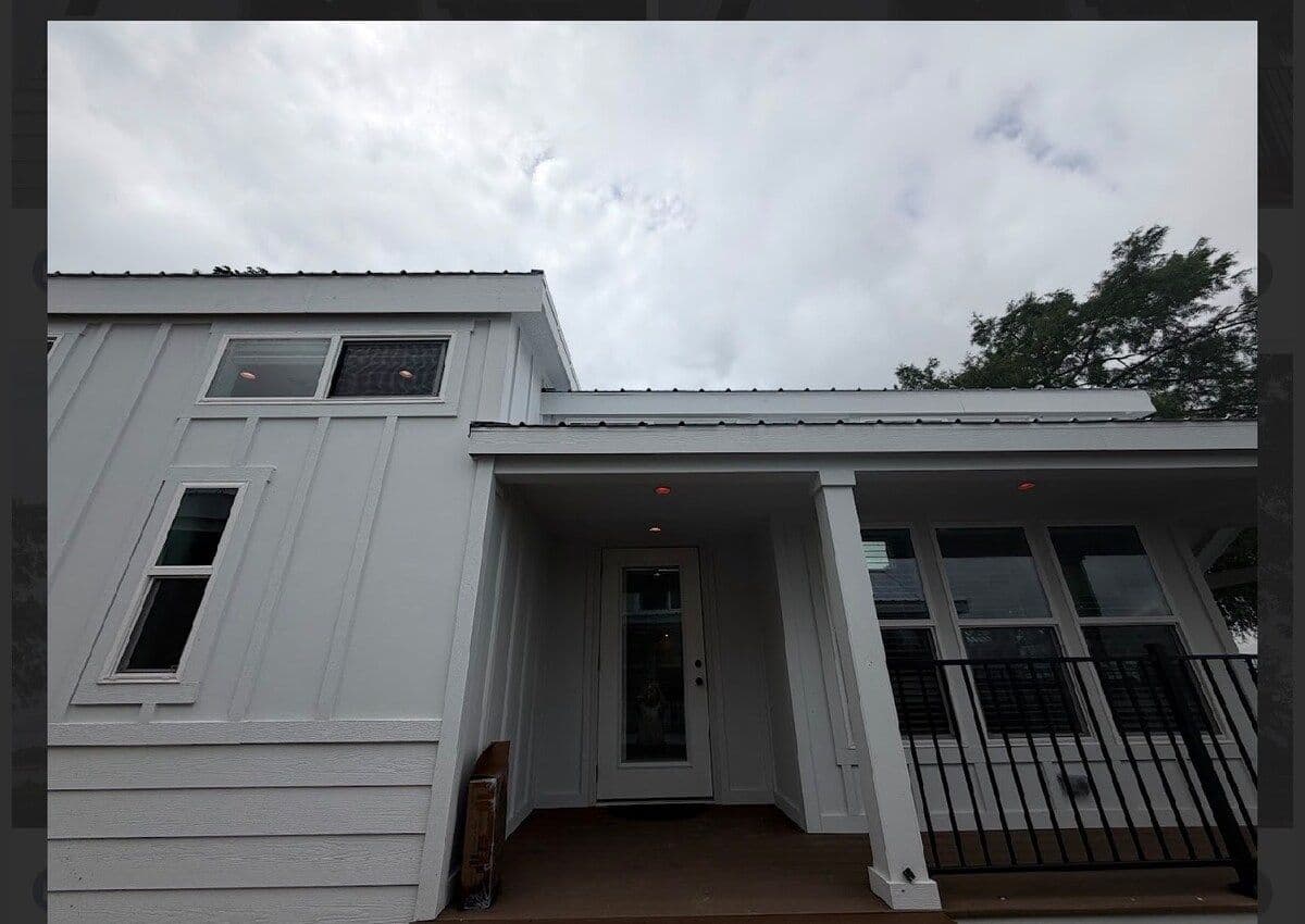 Home facade with white siding and covered porch under a cloudy sky