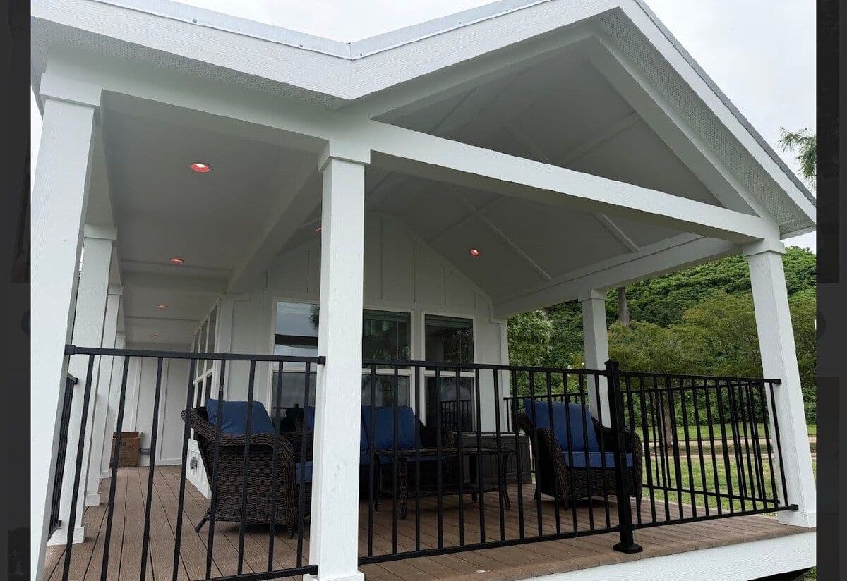 Covered porch with blue cushioned seating and black railing