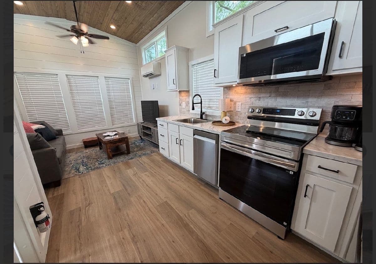 Kitchen with stainless range, microwave hood, white cabinets and wood floor