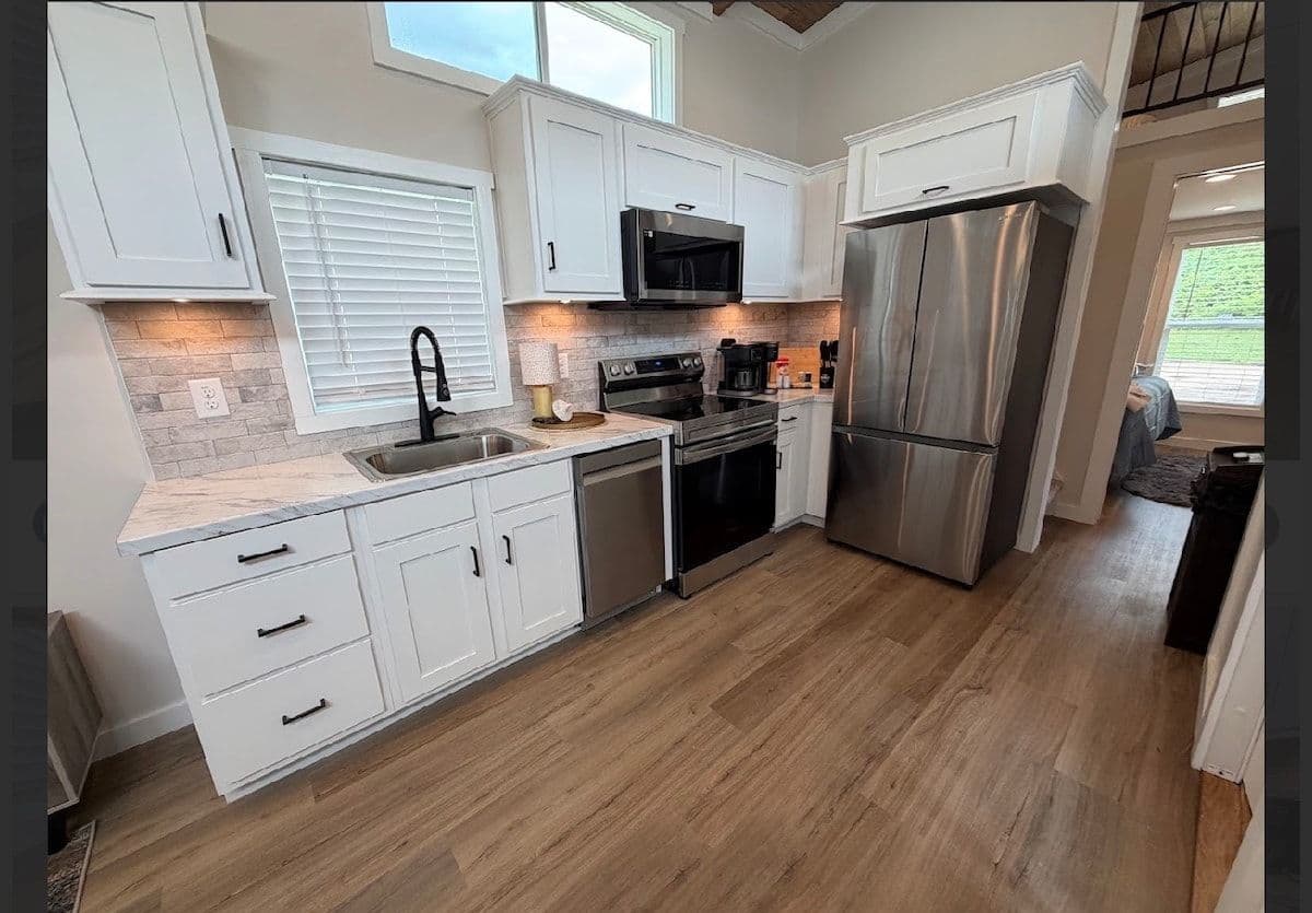 Kitchen with stainless fridge, white cabinets and window
