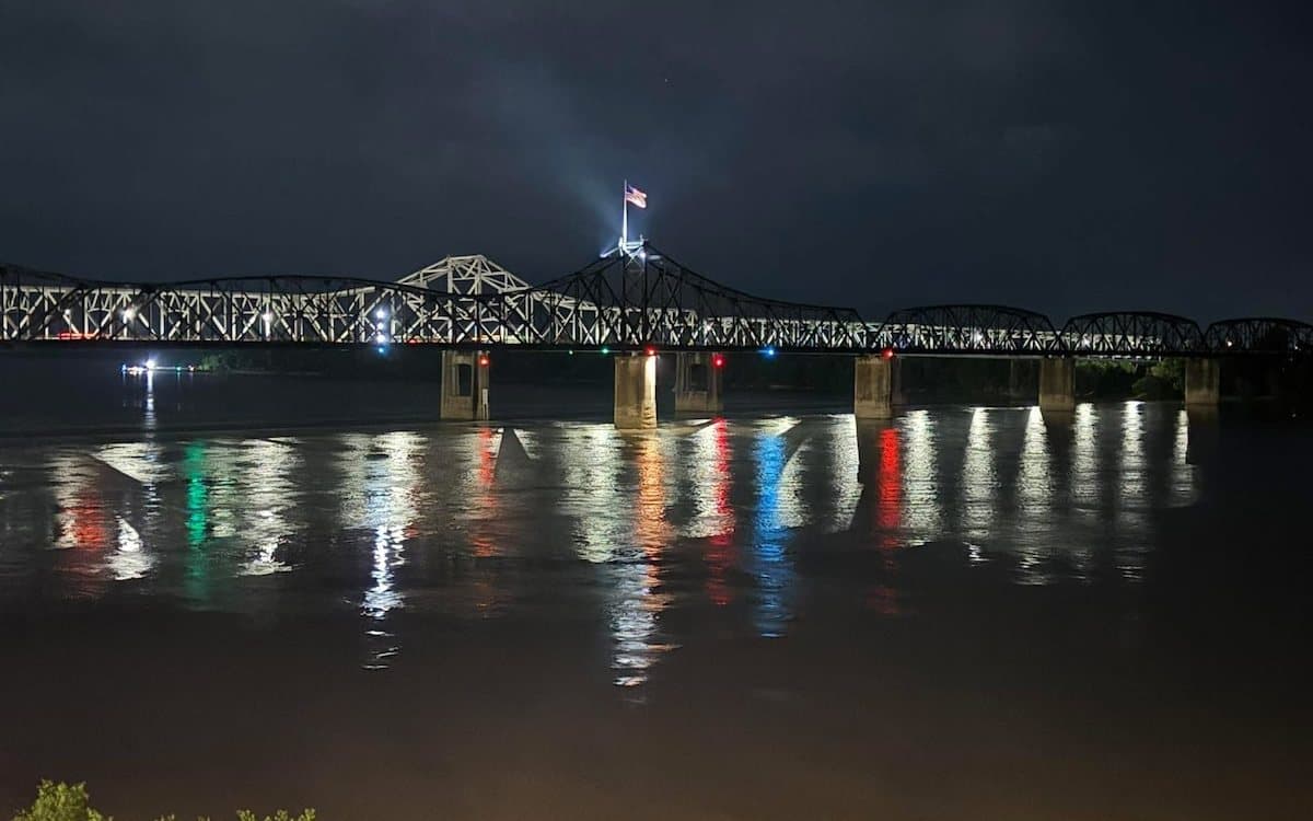 The Vicksburg bridge lit up at night, its lights reflected in the Mississippi