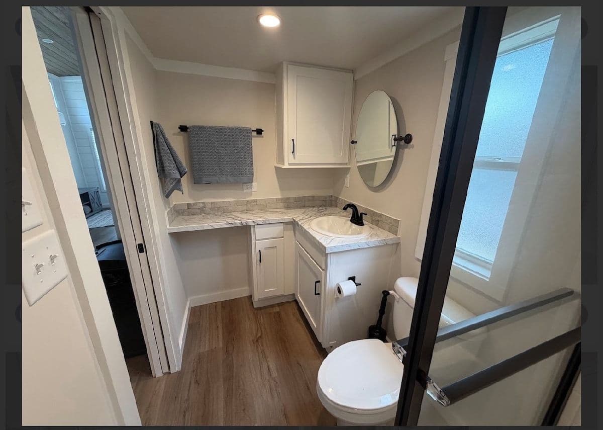 Bathroom vanity with mirror, toilet and glass shower edge