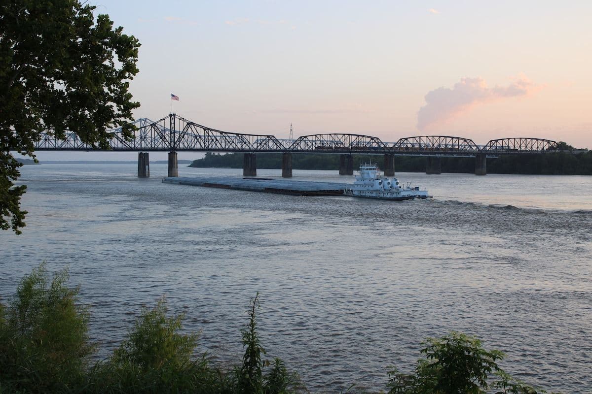 Dusk view of the Vicksburg bridge over the river with a towboat