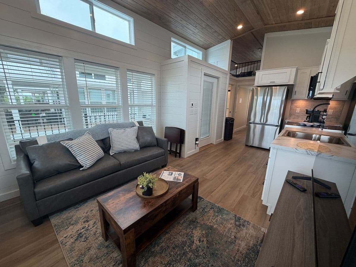 Living area with dark gray sofa, wood coffee table and wall of windows