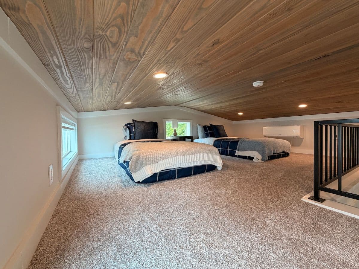 Loft with beds along the wall, rail and stair opening