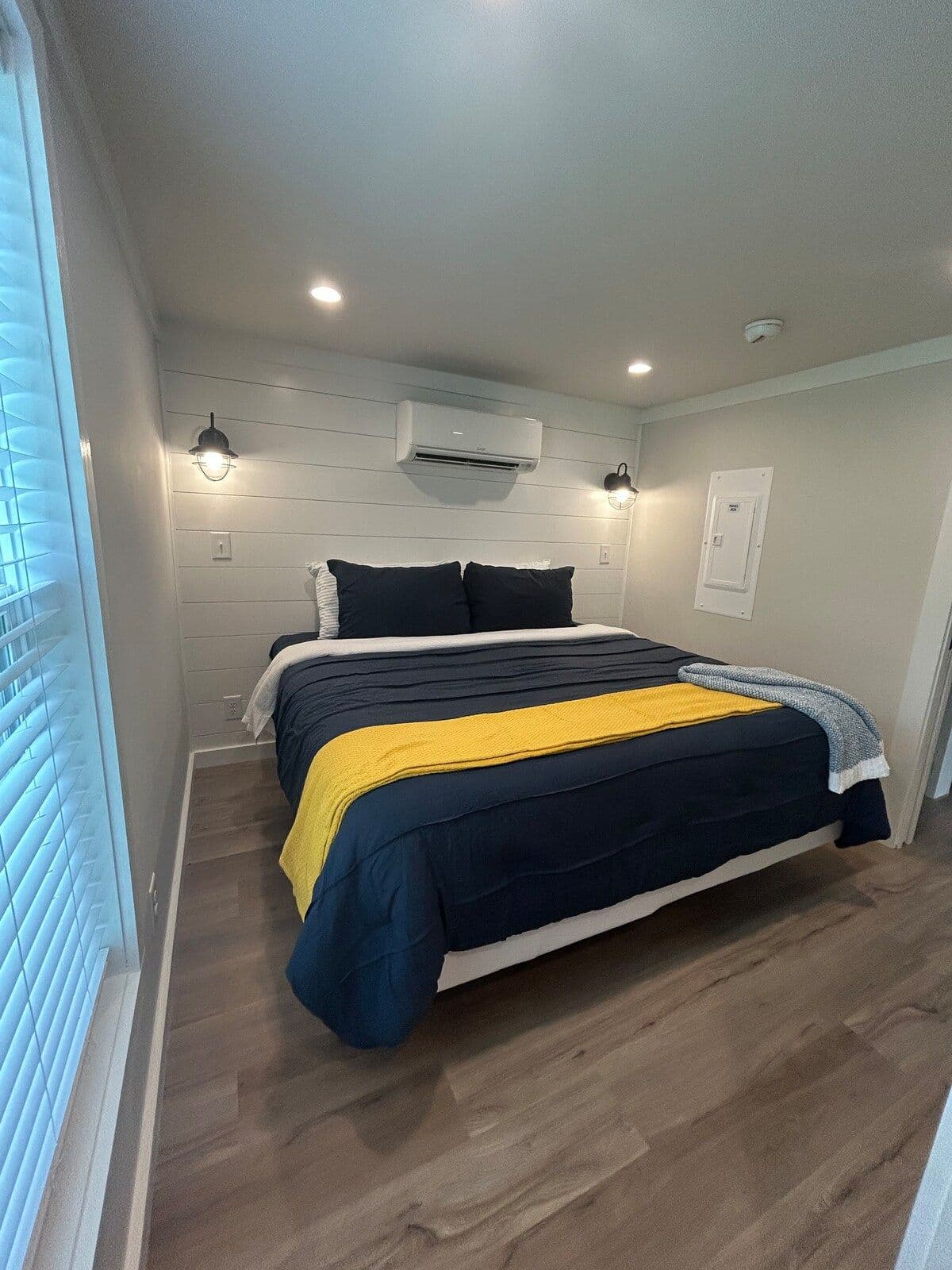 Bedroom with navy bedding and a yellow stripe, recessed lights