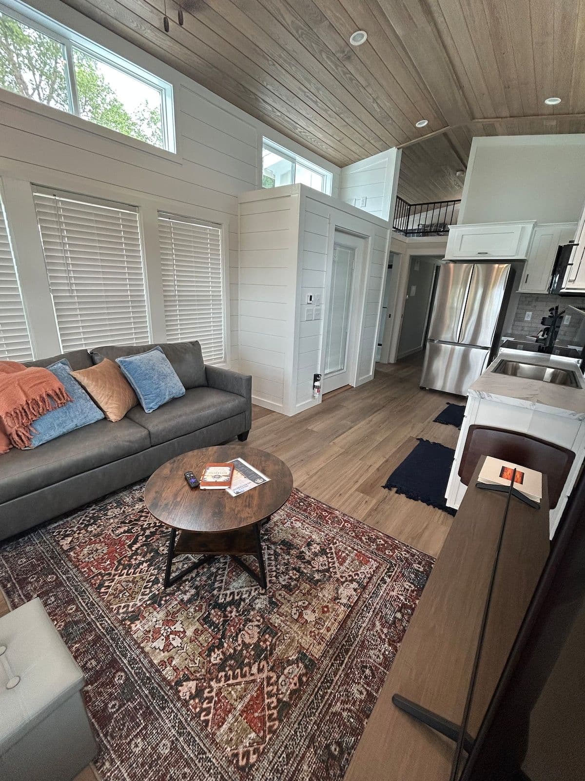 Living area with gray sofa, patterned rug and wood ceiling