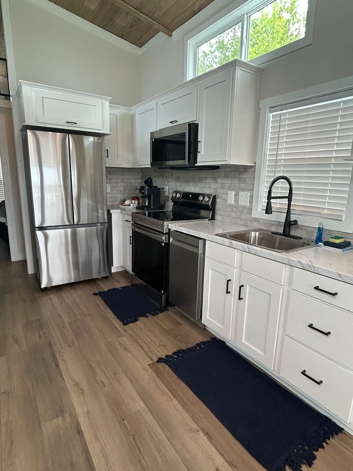 Kitchen with white cabinets, stainless fridge and navy floor mats