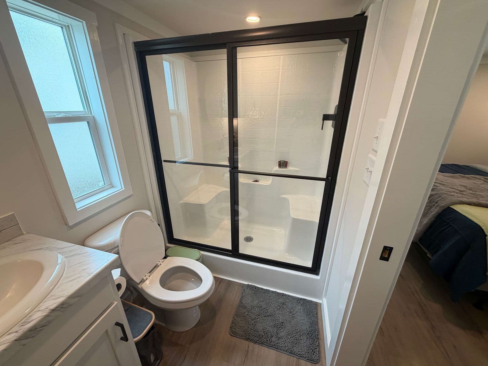 Bathroom with glass shower, window, vanity and toilet