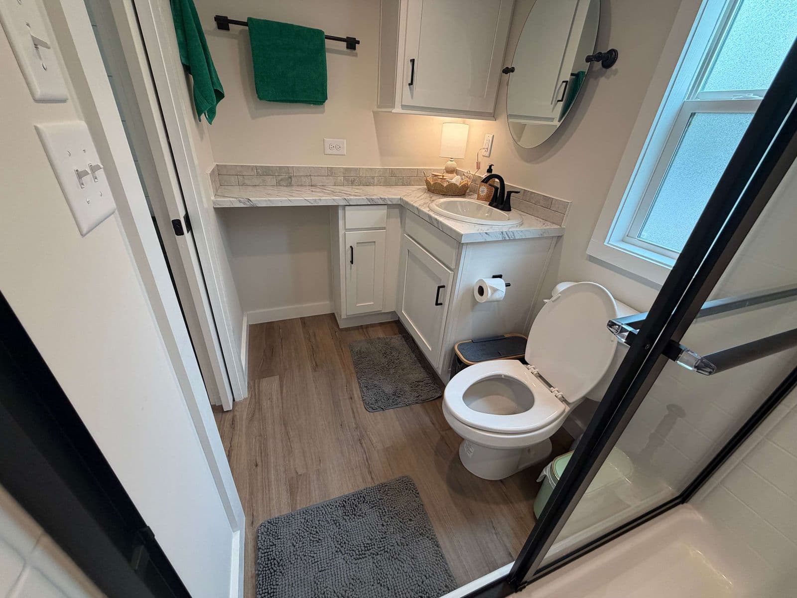 Bathroom vanity with green towel, toilet and shower edge