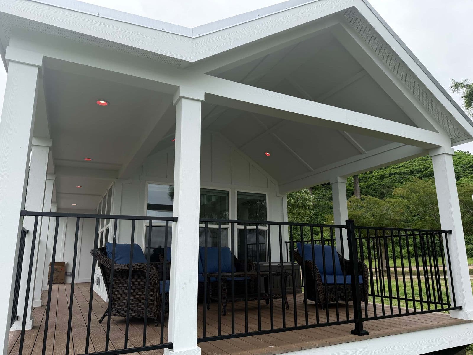 Covered porch from the lawn side with white columns and blue chairs