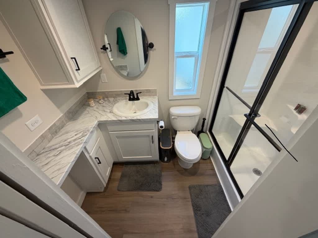 Bathroom with white vanity, round mirror, toilet and glass shower