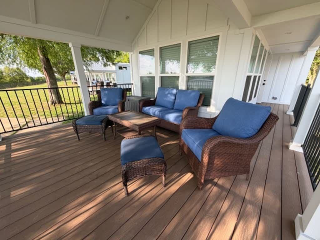 Covered porch with blue cushioned chairs and wooden floor