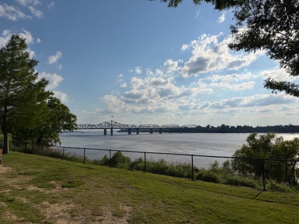 Lawn and river with the bridge under a blue sky