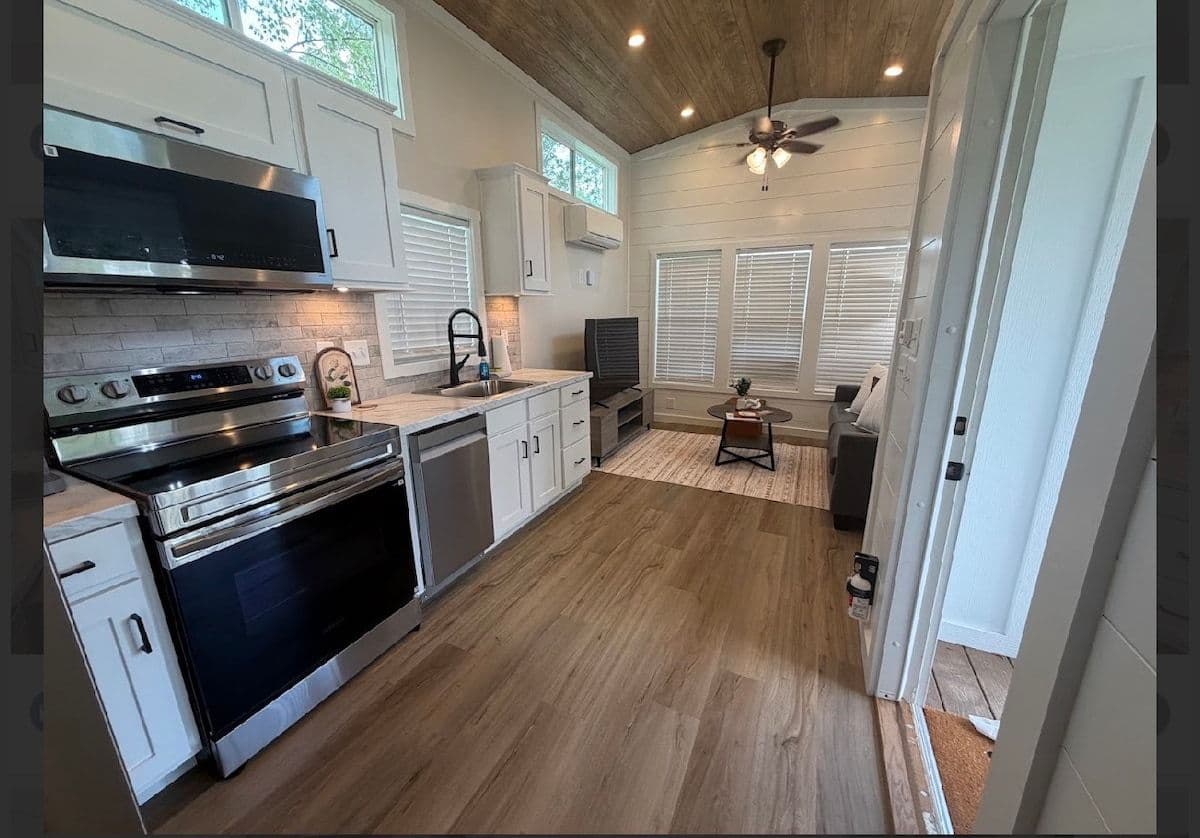 Kitchen with stainless range, vent hood, white cabinets and wood floor